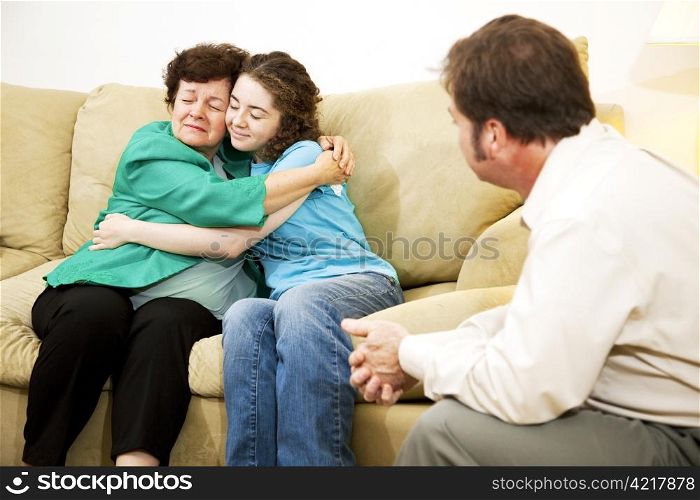 Mother and daughter hugging during a family counseling session with a therapist.
