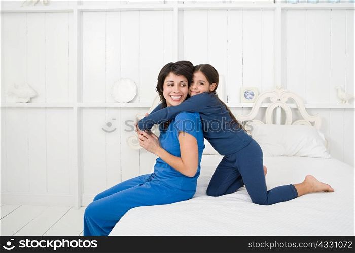 Mother and daughter hugging on bed