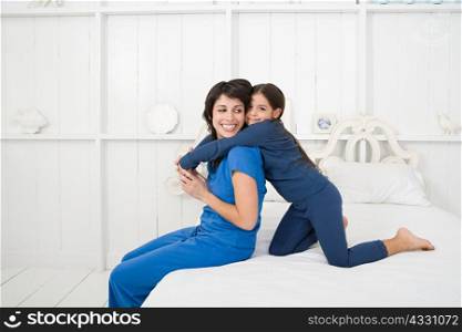 Mother and daughter hugging on bed