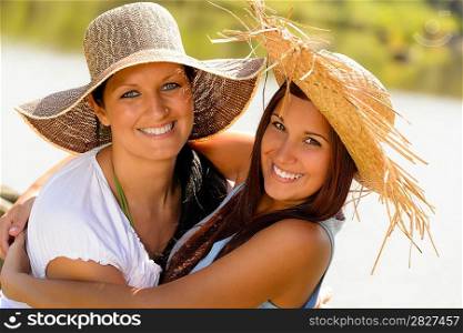Mother and daughter hugging outdoors summer teen vacation straw hats