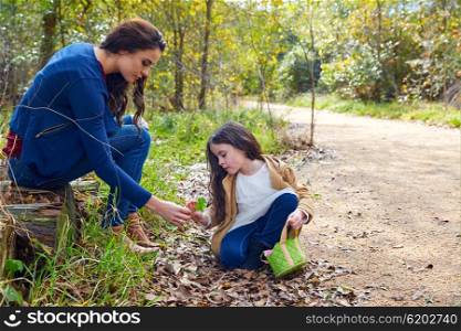 Mother and daughter in a park picking clover plants