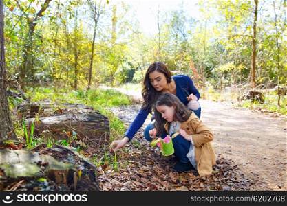 Mother and daughter in a park picking clover plants