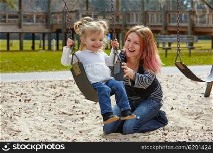Mother and daughter in a swing having fun at the park playground