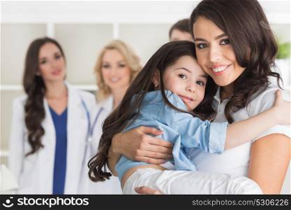 Mother and daughter in clinic. Mother and daughter in medical clinic, team of doctors on background