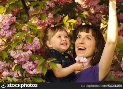 Mother and daughter in garden, under the sakura tree. Spring.