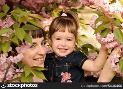 Mother and daughter in garden, under the sakura tree. Spring.