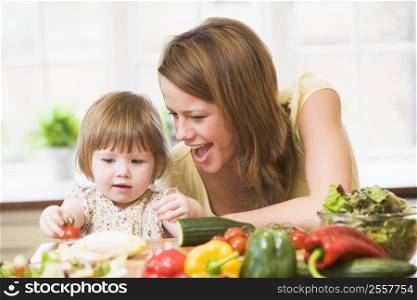 Mother and daughter in kitchen making a salad smiling