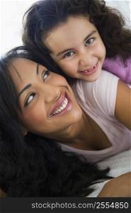 Mother and daughter in living room embracing and smiling (high key/selective focus)