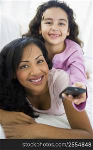 Mother and daughter in living room with remote control smiling (high key/selective focus)