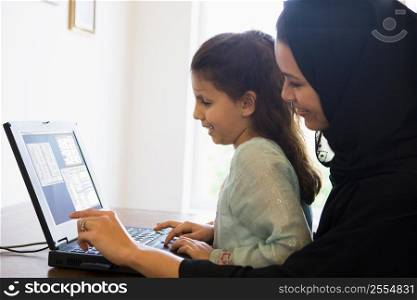 Mother and daughter in office with laptop smiling (high key/selective focus)