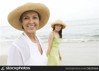 Mother and daughter in sunhats on beach