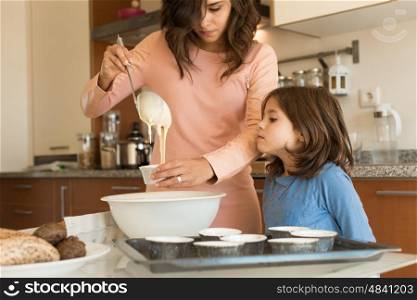 Mother and daughter in the kitchen cooking cupcakes