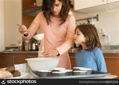 Mother and daughter in the kitchen cooking cupcakes