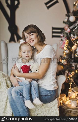 Mother and daughter in the white chair in front of a huge clock.. Family portrait in front of a huge white pointer hours 7260.