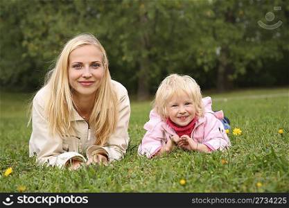 mother and daughter lie on the grass