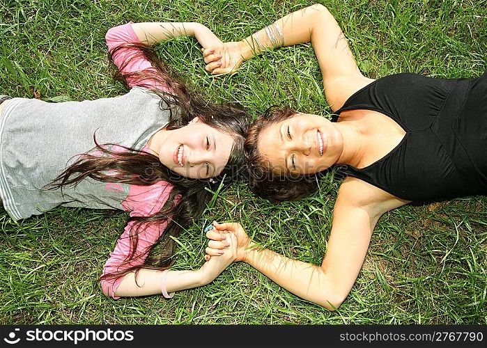 mother and daughter lie on the grass