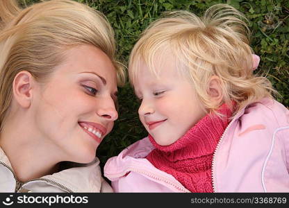 mother and daughter lie on the grass and look at each other