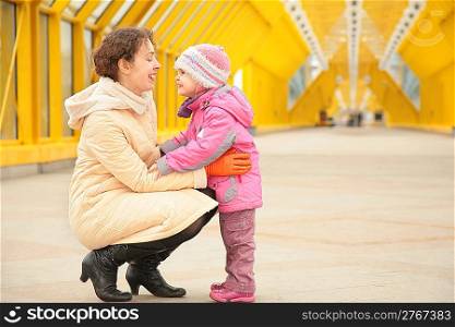 mother and daughter look each other on footbridge