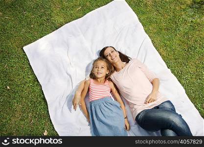 Mother and daughter lying on blanket, high angle