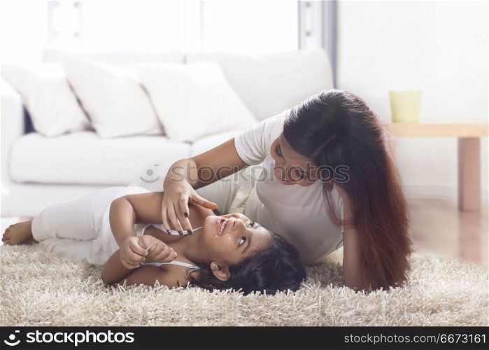 Mother and daughter lying on carpet at home