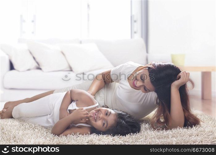 Mother and daughter lying on carpet in living room