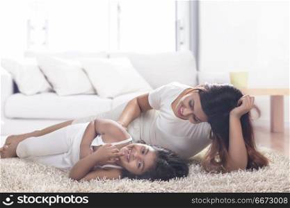 Mother and daughter lying on carpet in living room