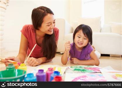 Mother And Daughter Lying On Floor And Painting Picture