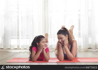 Mother and daughter lying on yoga mat