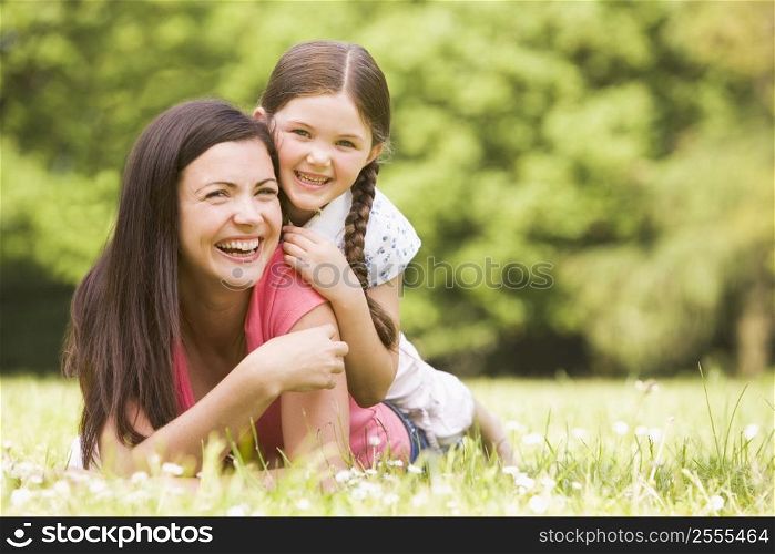 Mother and daughter lying outdoors smiling