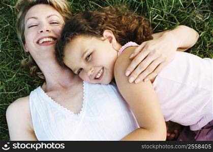 Mother and daughter lying outdoors smiling