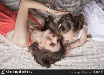Mother and daughter lying with their heads towards each other on the bed.. Portrait of a little girl and her mother lying on the bed 9429.