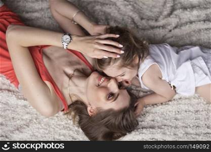 Mother and daughter lying with their heads towards each other on the bed.. Portrait of a little girl and her mother lying on the bed 9430.