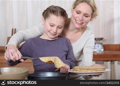 Mother and daughter making crepes together