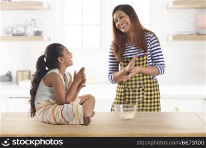 Mother and daughter making dough balls in kitchen