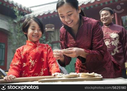 Mother and daughter making dumplings in traditional clothing
