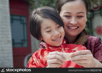 Mother and daughter making dumplings in traditional clothing, close up