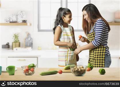 Mother and daughter making vegetable salad in kitchen