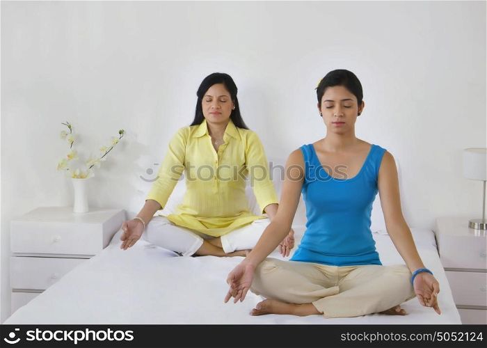 Mother and daughter meditating together