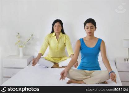 Mother and daughter meditating together