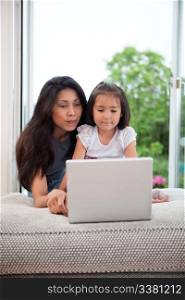 Mother and daughter on couch using laptop