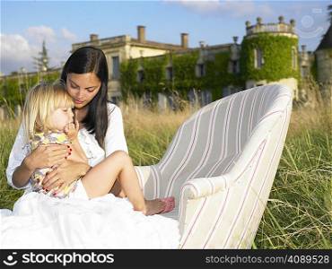 Mother and daughter on sofa in a field