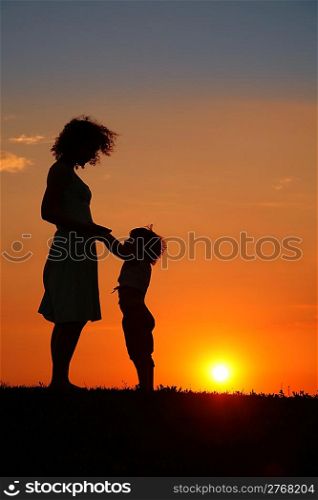 Mother and daughter on sunset silhouette