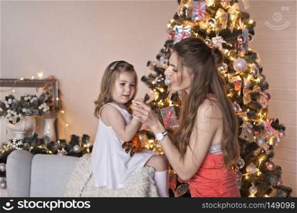 Mother and daughter on the background of sparkling Christmas garlands.. Portrait of beautiful girl with her daughter on the background of sparkling