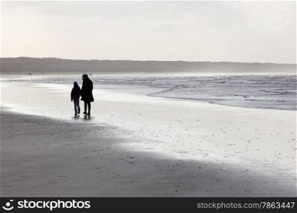 mother and daughter on windy beach in the netherlands