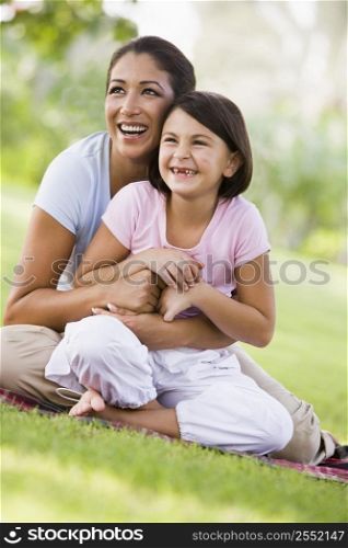 Mother and daughter outdoors in park smiling (selective focus)