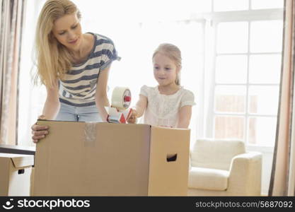 Mother and daughter packing cardboard box at home