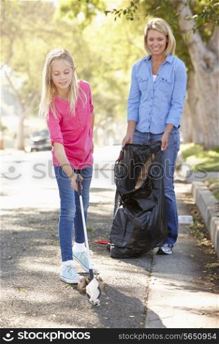 Mother And Daughter Picking Up Litter In Suburban Street