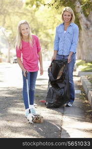 Mother And Daughter Picking Up Litter In Suburban Street