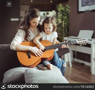 Mother and daughter playing a classic guitar