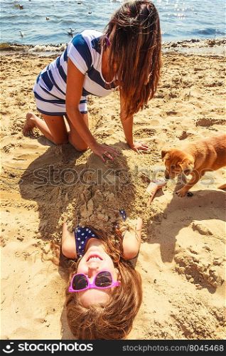 Mother and daughter playing on beach.. Play and fun in summer. Adorable girl daughter having fun with her mommy. Family spending time together on beach seaside.
